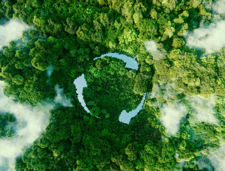 Ein Wald von oben aus der Luft fotografiert mit Wolken und einem See der das Recyclingzeichen darstellt.
